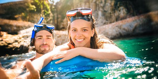 Eine Mann und eine Frau sind im Wasser und tragen eine Taucherbrille mit Schnorchel. 