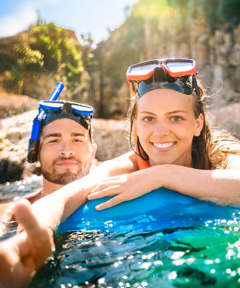 Eine Mann und eine Frau sind im Wasser und tragen eine Taucherbrille mit Schnorchel. 