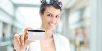 Eine Frau hält eine Kreditkarte in die Kamera.