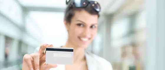 Eine Frau hält eine Kreditkarte in die Kamera.