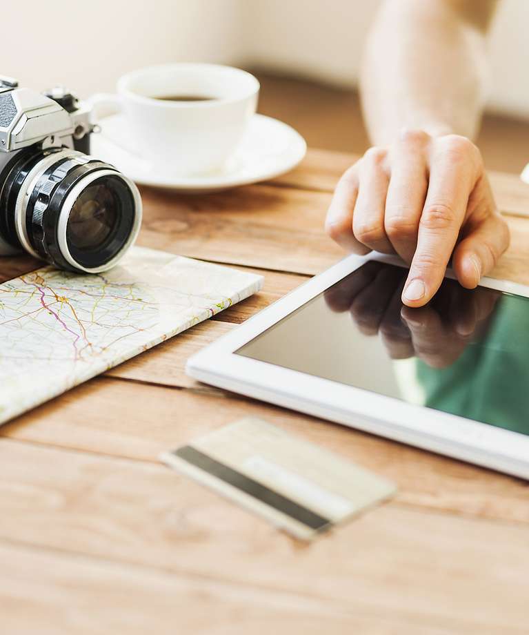 Ein Tablett liegt auf einem Tisch. Daneben liegt eine Kamera, eine Landkarte und eine Tasse.