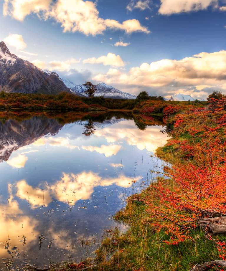 Man sieht eine farbenfrohe Landschaft mit Bergen und See.