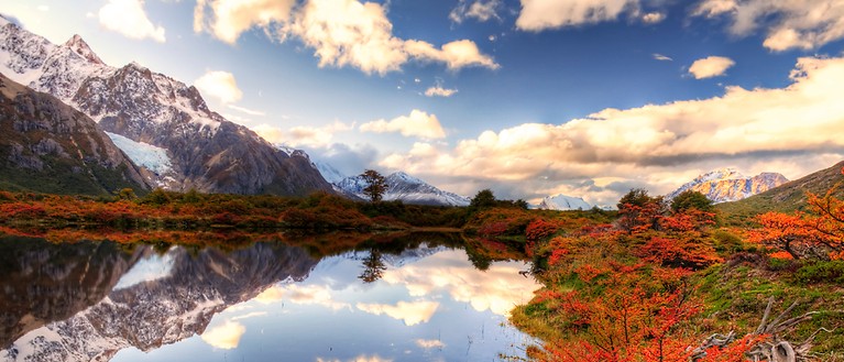 Man sieht eine farbenfrohe Landschaft mit Bergen und See.