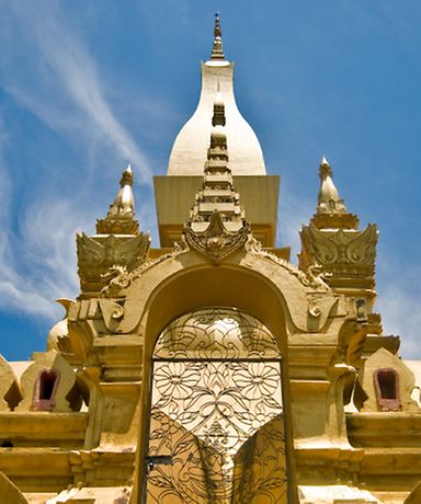 Man sieht einen Eingang zu einem sandfarbenen Tempel.