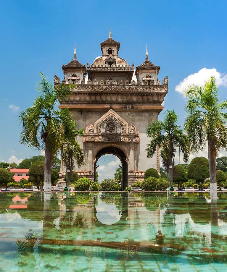 Man sieht einen Eingang zu einem sandfarbenen Tempel.