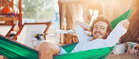 Ein Mann liegt in einer Hängematte am Strand.