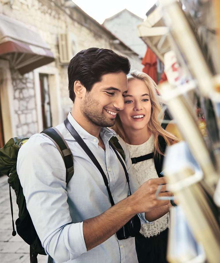 Zwei Touristen schauen sich gemeinsam Postkarten an. 