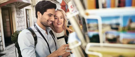 Zwei Touristen - Jahres-Auslandskrankenversicherung Zwei Touristen schauen sich gemeinsam Postkarten an.