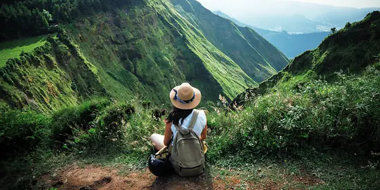Eine Frau sitzt vor einer grünen Bergkulisse. 
