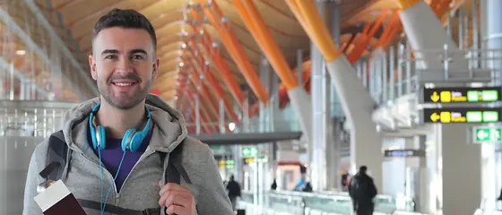 Ein Mann am Flughafen - Reise-Krankenversicherung Ein Mann steht mit einem Reisepass in der Hand am Flughafen.