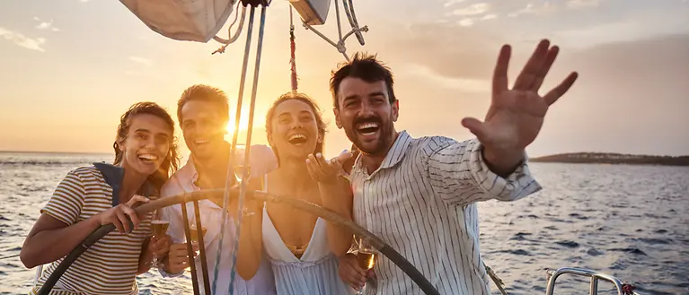 Junge Leute auf Segelyacht, im Hintergrund geht die Sonne unter