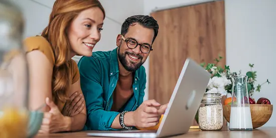 A couple are sitting together at a laptop.