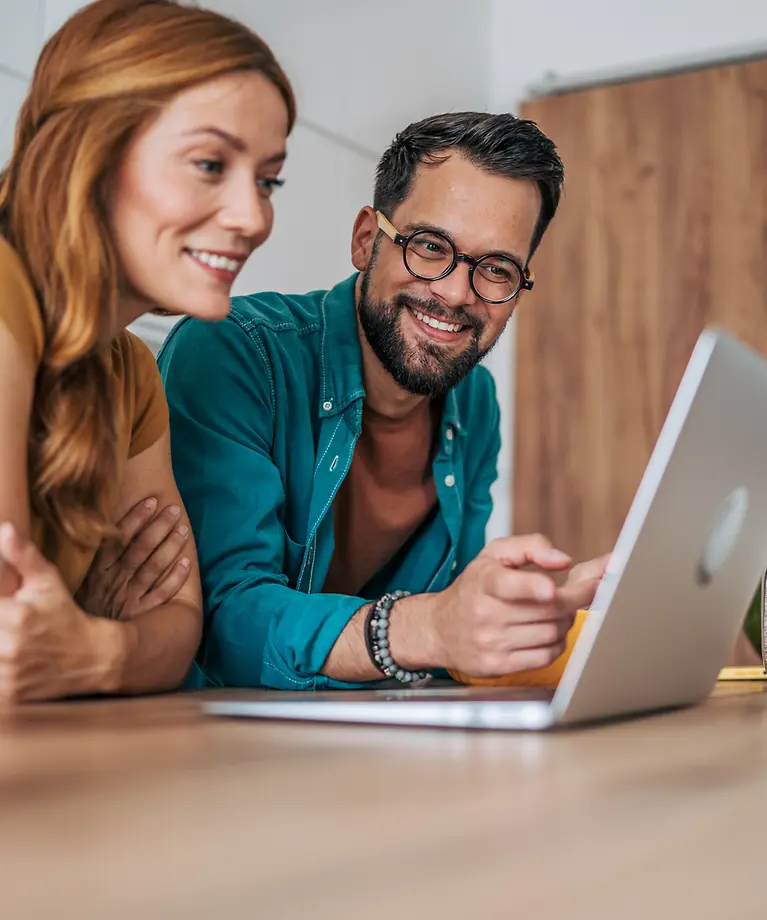 A couple are sitting together at a laptop.