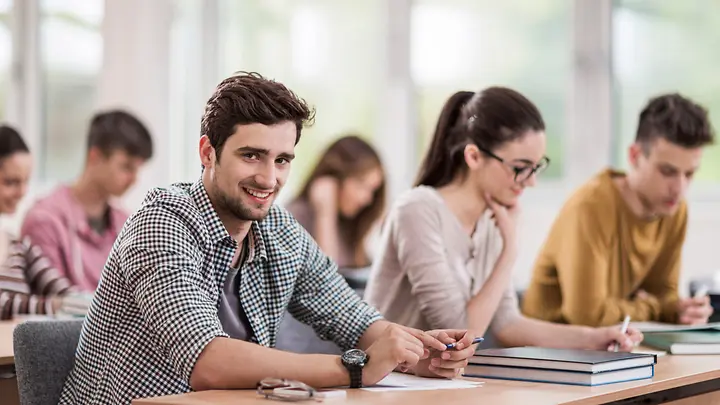 Schüler im Klassenraum - Erasmus Reiseschutz Sechs Personen sitzen in einem Raum und lernen.