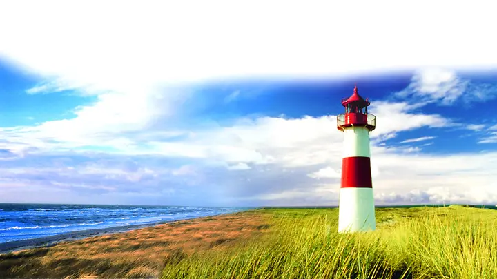 Auf dem Foto ist ein Leuchtturm in rot und weiß zu sehen. Um den Leuchtturm herum ist Wasser und Wiese. 