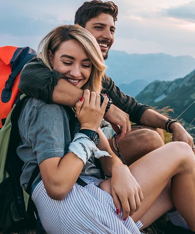 Paar mit Rucksack vor Bergkulisse