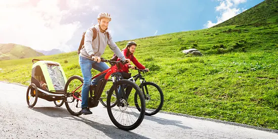 Ein Mann und eine Frau sitzen auf einem E-Bike und machen eine Tour in den Bergen. 