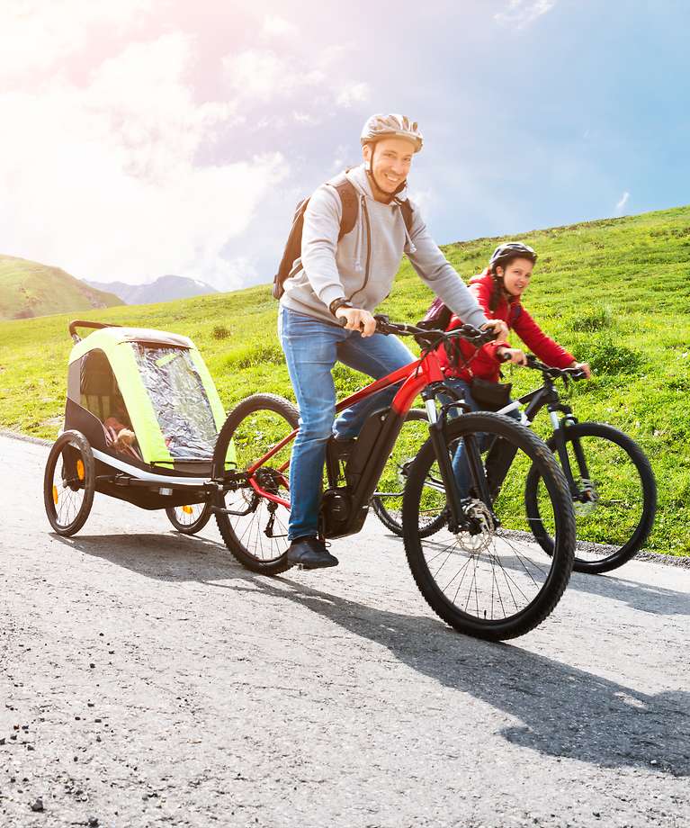 Ein Mann und eine Frau sitzen auf einem E-Bike und machen eine Tour in den Bergen. 