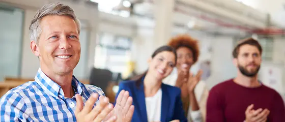 Vortrag - Seminarversicherung Vier Personen sitzen auf Stühlen und klatschen.